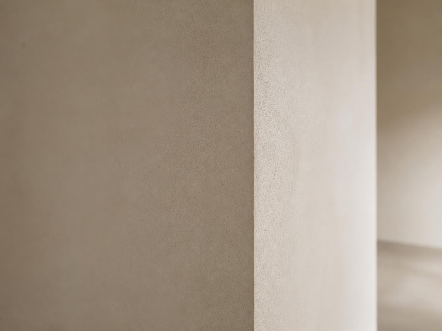 Detail van een strak gestucte wand met scherpe hoekafwerking